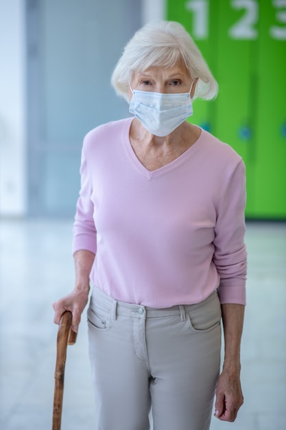 Femme âgée dans un masque facial marchant dans le couloir