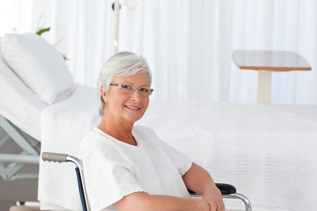 Femme âgée dans son fauteuil roulant en regardant la caméra