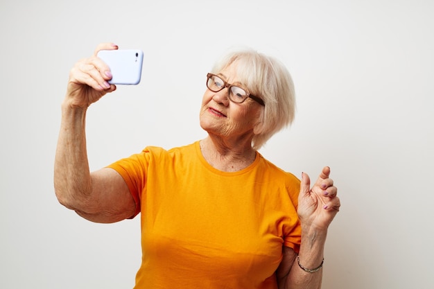 Femme âgée dans un t-shirt jaune posant la communication par téléphone émotions gros plan