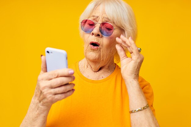 Femme âgée dans des verres à la mode avec un smartphone gros plan émotions