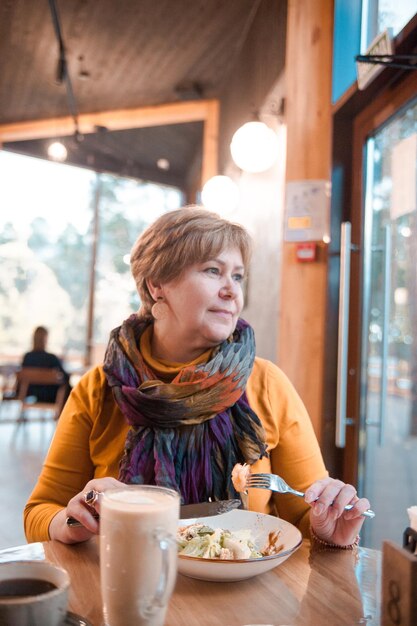 Femme âgée déjeunant au café avec salade César et café