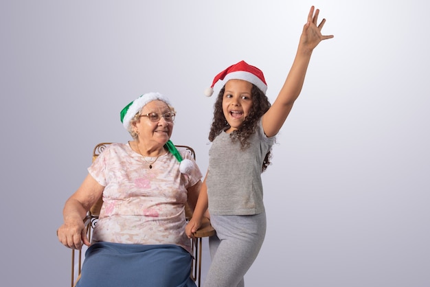 Femme âgée et enfant avec chapeau de Noël sur fond gris