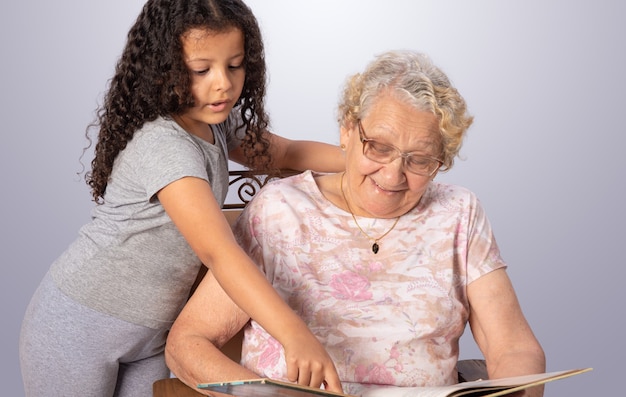 Femme âgée et enfant lisant un livre sur gris