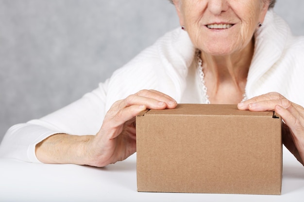 Photo une femme âgée entre 70 et 80 ans montre une boîte en carton sur la table. fermer