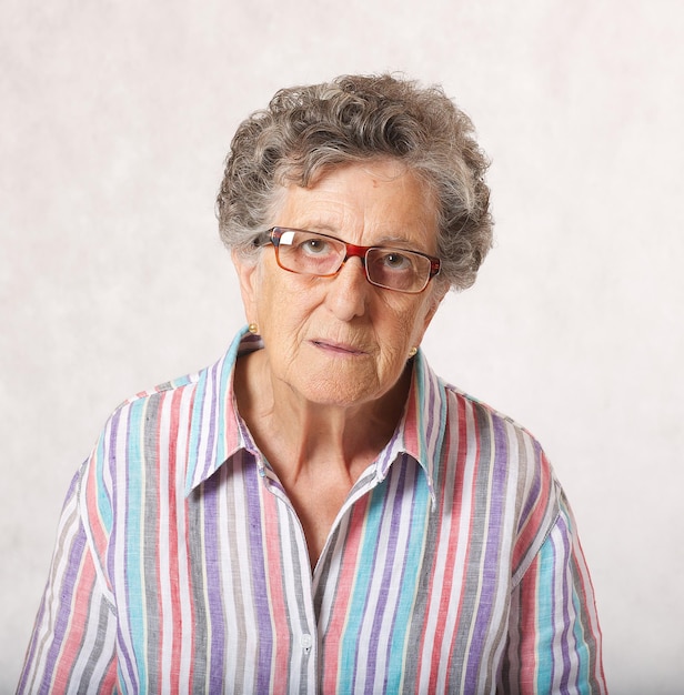 Une femme âgée entre 70 et 80 ans pense à quelque chose. Fond gris