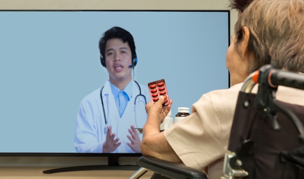 Une femme âgée est assise à la maison après avoir consulté un médecin en ligne.