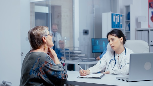 Femme âgée faisant un examen de la gorge au bureau du médecin. Mise au point sélective. Soins de santé dans un hôpital moderne ou une clinique privée, prévention des maladies et consultation dans les diagnostics de médicaments de traitement de bureau médical