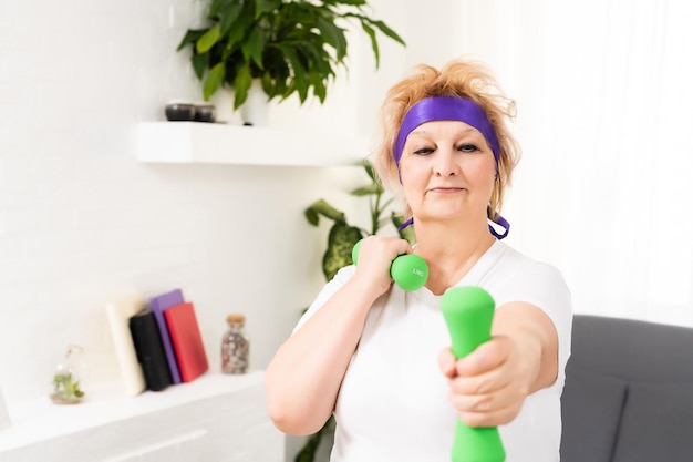 Femme âgée faisant des exercices physiques avec un haltère.