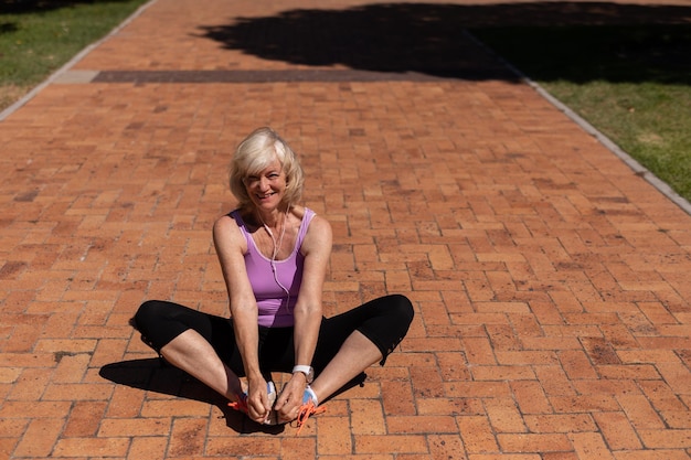 Photo une femme âgée fait du yoga sur le trottoir dans le parc.