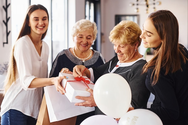 Femme âgée avec famille et amis célébrant un anniversaire à l'intérieur.