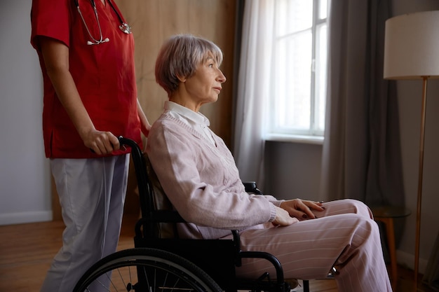 Une femme âgée en fauteuil roulant bénéficiant d'une aide professionnelle dans une maison de retraite