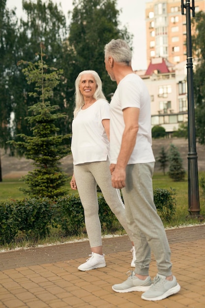 Femme âgée gaie dans des vêtements sportifs marchant main dans la main avec son homme