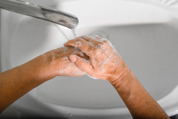 Une femme âgée en gros plan se lave les mains avec du savon et de la mousse dans un évier désinfecte la Journée mondiale du lavage des mains