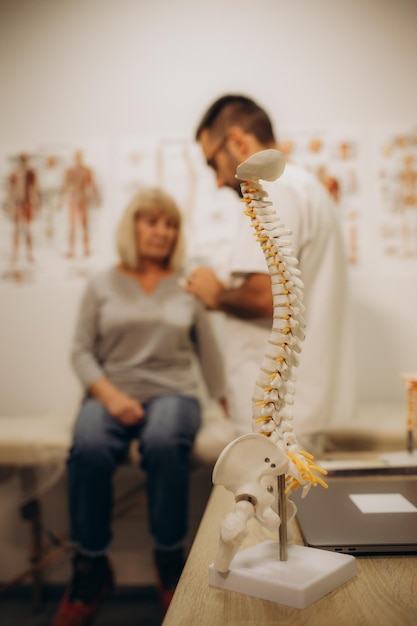 Une femme âgée heureuse allongée sur un canapé d'examen pendant qu'un chiropraticien ostéopathe ou un physiothérapeute examine son dos Traitement de l'ostéoporose concept de physiothérapie de la physiothérapie