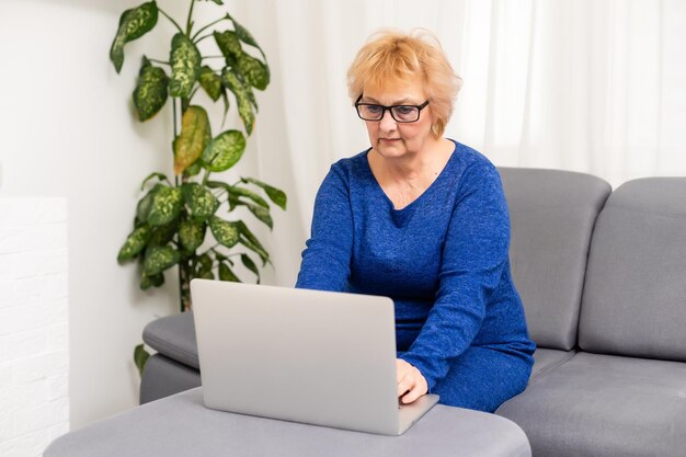 femme âgée heureuse utilisant un ordinateur portable à la maison.