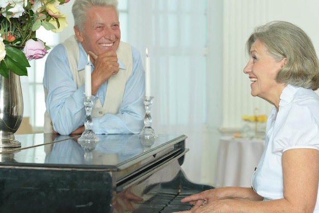 Femme âgée jouant du piano à la maison avec son mari