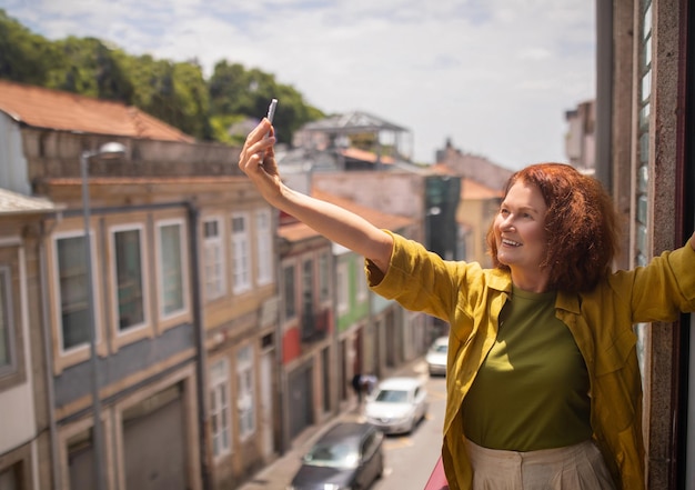 Photo une femme âgée joyeuse tendant son bras et prenant un selfie sur le balcon