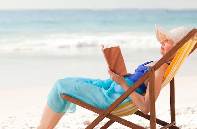 Femme âgée lisant un livre à la plage