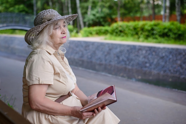 Une femme âgée lit un livre dans le parc