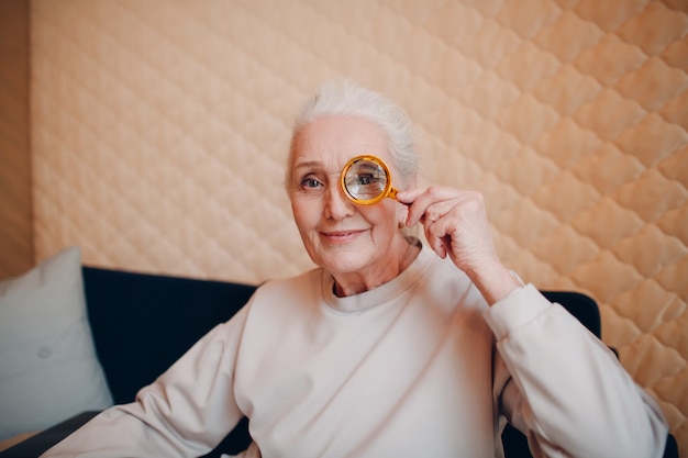 La femme âgée avec une loupe à la main