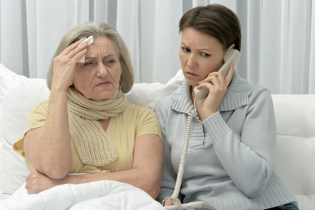 Femme âgée malade avec une fille inquiète et attentionnée avec un téléphone