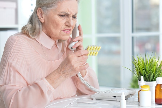 Femme âgée malade avec des médicaments appelant à l'hôpital