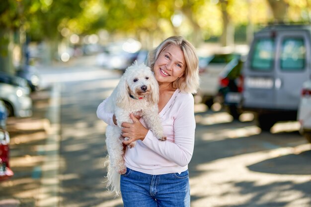 Femme âgée marchant avec un chien à l'extérieur.