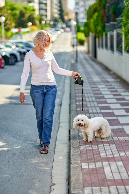 Femme âgée marchant avec un chien à l'extérieur.