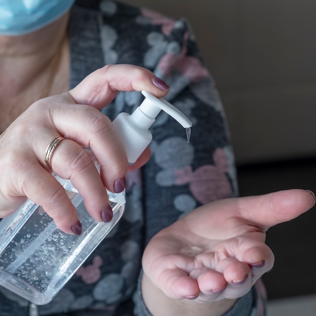 Photo femme âgée avec un masque de protection à l'aide de gel antiseptique alcool. épidémie de coronavirus .