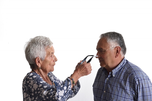 Une femme âgée met des lunettes à un homme plus âgé