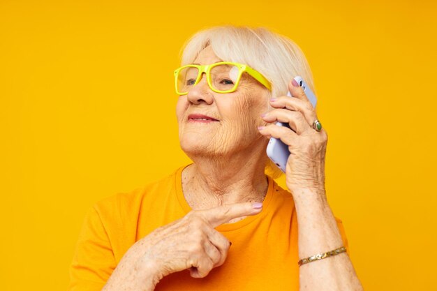 Femme âgée mode de vie heureux en t-shirts jaunes avec des émotions de gros plan de téléphone