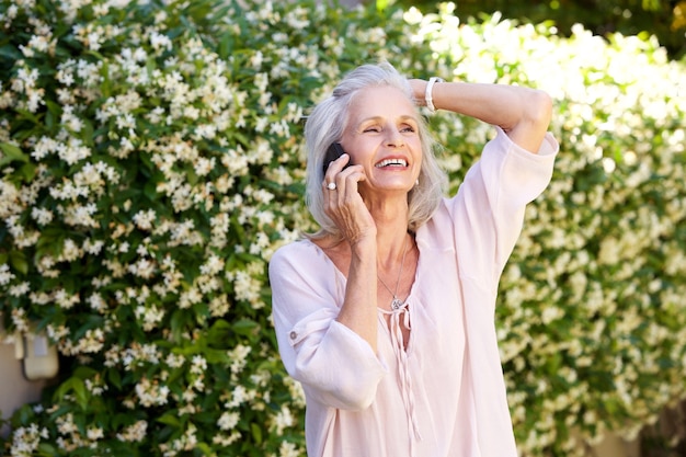 Femme âgée parlant au téléphone avec la main à la tête à l&#39;extérieur