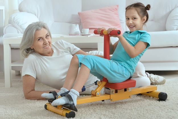 Femme âgée et petite-fille faisant de l'exercice à la maison