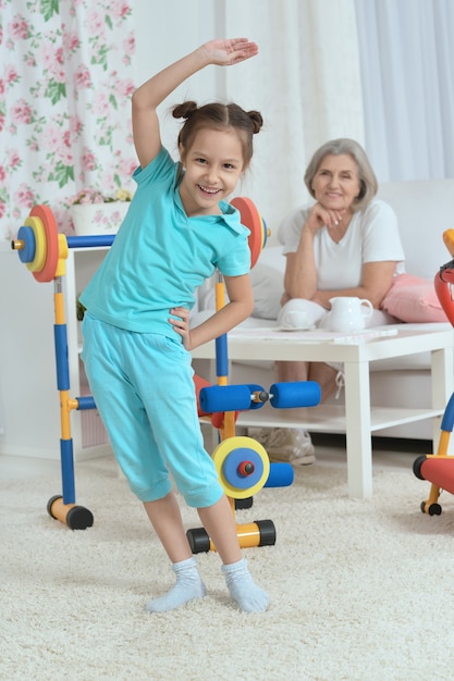 Femme âgée et petite-fille faisant de l'exercice à la maison