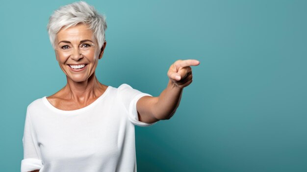 Femme âgée portant une chemise blanche pointant avec la main et le doigt sur le côté en regardant la caméra