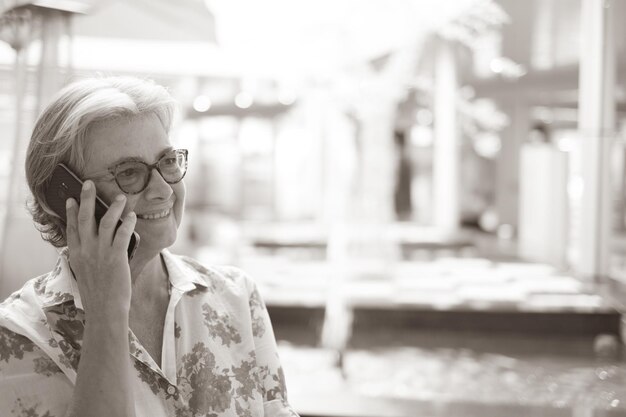 Photo une femme âgée portant des lunettes de soleil en parlant au téléphone dans un centre commercial