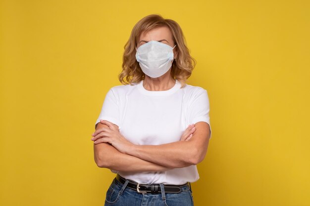 Femme âgée portant un masque de protection sur un mur jaune