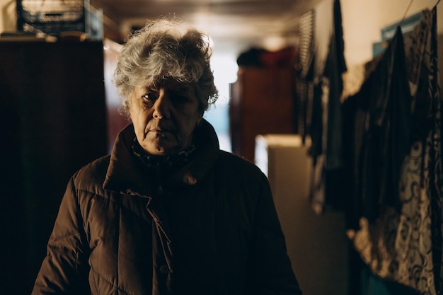 Une femme âgée portant une veste dans un couloir sombre d'un ancien dortoir soviétique où vivent des personnes pauvres et socialement vulnérables