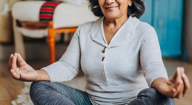 une femme âgée pratiquant le yoga à la maison dans la pose du lotus