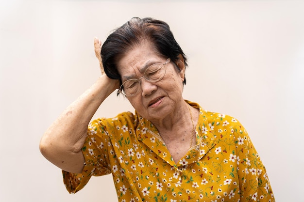 Une femme âgée qui a un mal de tête sévère souffre d'un accident vasculaire cérébral malade tenant la tête avec sa main souffrant de démence sénile troubles de la mémoire confondu vieux personnes âgées avec Alzheimer