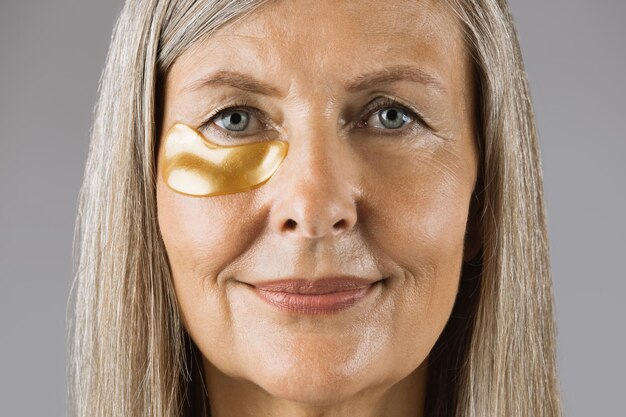 Femme âgée qui pose en studio avec des patchs sous les yeux