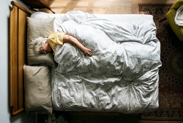 Femme âgée de race blanche dormant sur le lit