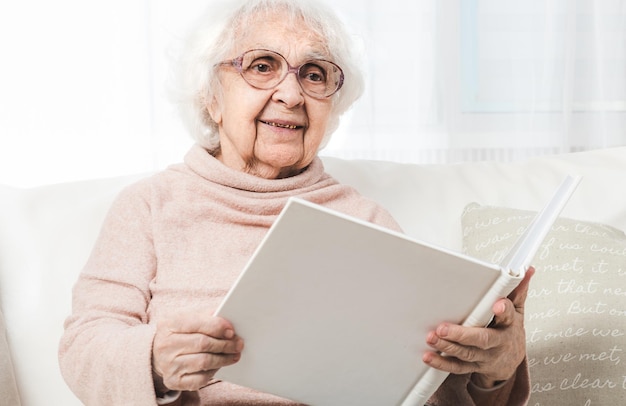 Femme âgée à la recherche de photos dans un album photo blanc