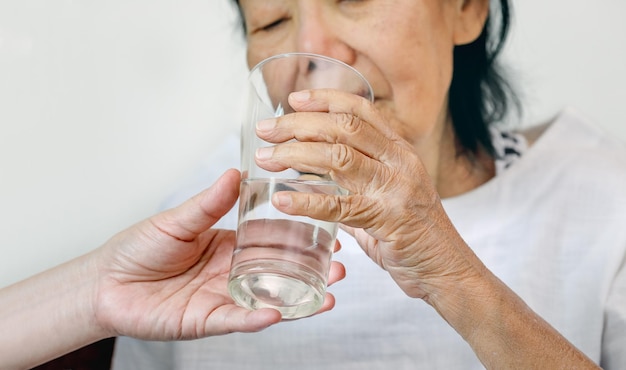 Une femme âgée reçoit un verre d'eau d'un soignant