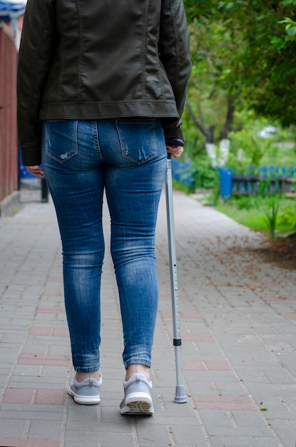 Femme âgée en rééducation après une chirurgie ou en convalescence marche avec une canne en plein air.