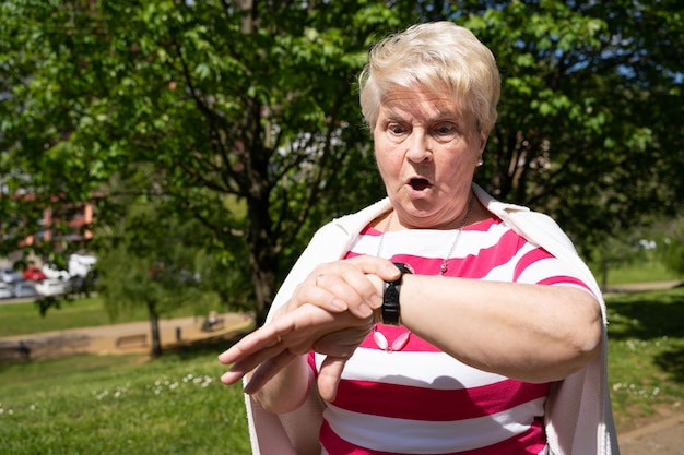 Femme âgée regardant regarder avec surprise regard au parc Dame blonde senior réalisant qu'elle est en retard