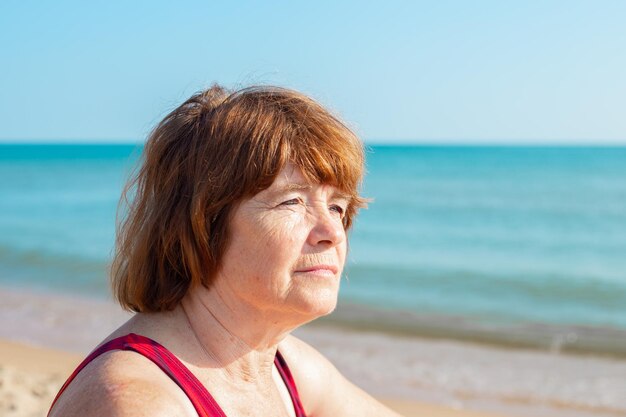 Une femme âgée regarde ailleurs la côte de la mer Vacances de retraite un jour d'été