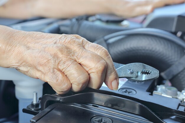 Femme âgée réparant sa voiture