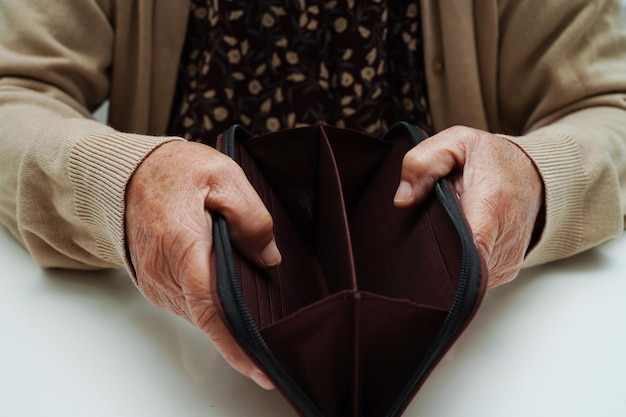 Une femme âgée à la retraite comptant des pièces de monnaie et s'inquiète des dépenses mensuelles et du paiement des frais de traitement
