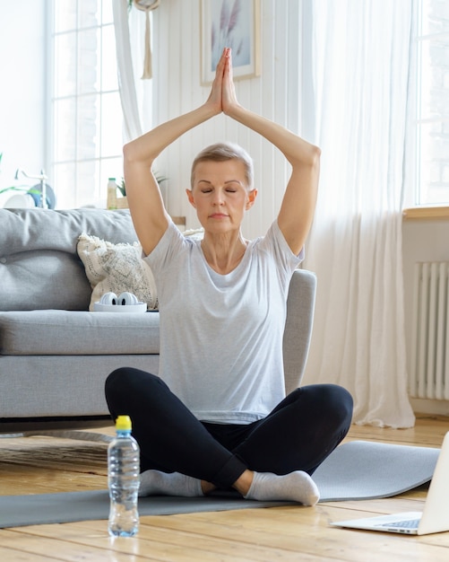 Une femme âgée à la retraite profite d'un yoga d'épanouissement personnel à la maison bien-être à la maison